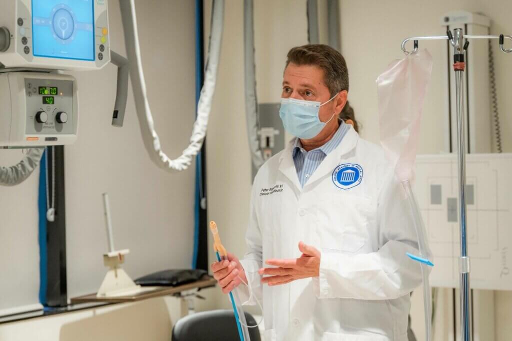 Man wearing a whitecoat in a Gurnick Academy lab. | Gurnick Academy of Medical Arts